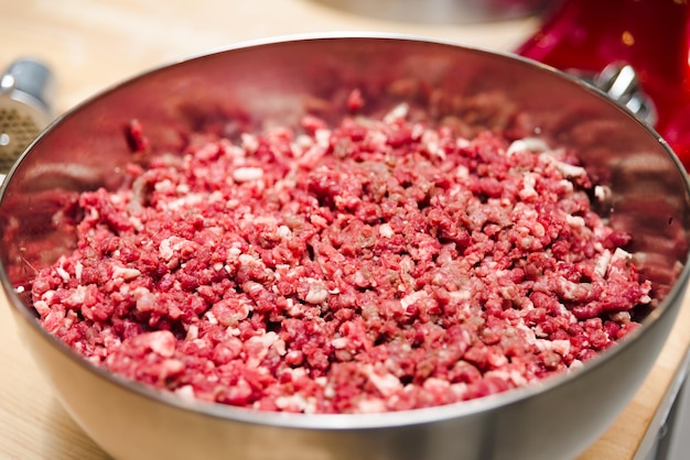 Viande hachée dans un bol en acier profond sur une table en bois se bouchent