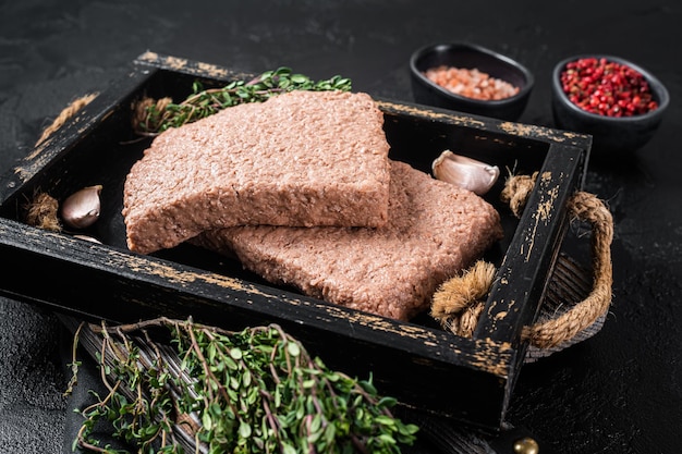 Viande hachée végétalienne crue à base de plantes avec des herbes. Fond noir. Vue de dessus.