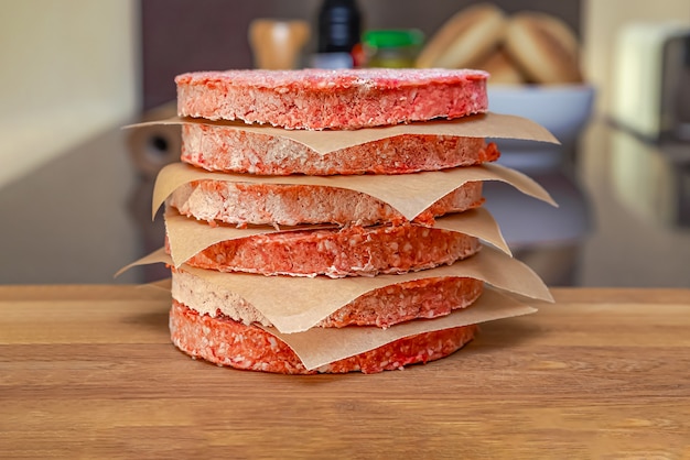 Viande de hamburger congelée sur table avant de griller, décongeler avant de griller.