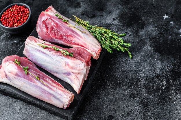 La viande de jarret de chèvre crue sur une planche de marbre. Table noire. Vue de dessus. Copiez l'espace.