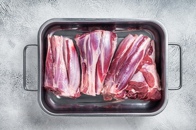 Viande de jarrets d'agneau crus frais dans un plateau en acier Fond blanc Vue de dessus