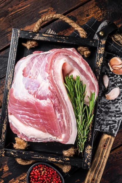 Viande de lard cru de poitrine de porc non cuite biologique dans une assiette en bois avec du thym Fond en bois Vue de dessus