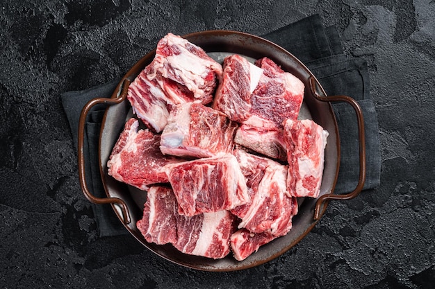 Viande marbrée de boeuf et d'agneau en dés crus dans un plateau en acier de cuisine Fond noir Vue de dessus