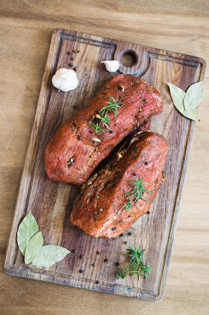 Viande marinée crue fraîche sur une table en bois.