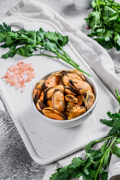 Viande de moule bouillie sur une planche à découper. Fruits de mer sains. Fond clair.