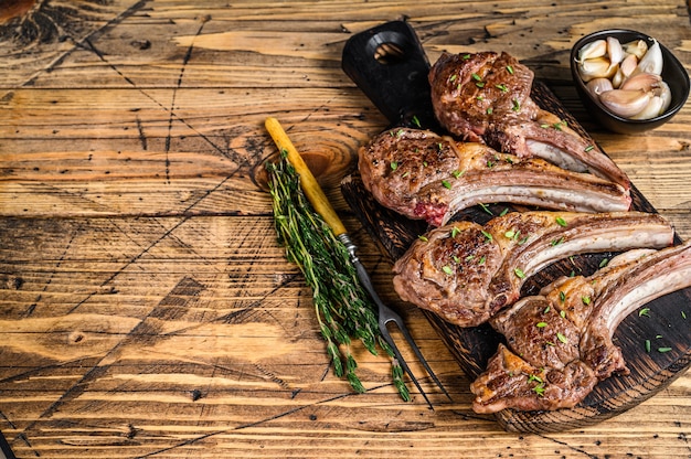 La viande de mouton d'agneau grillée coupe des steaks sur une planche à découper. fond en bois. Vue de dessus. Espace de copie.