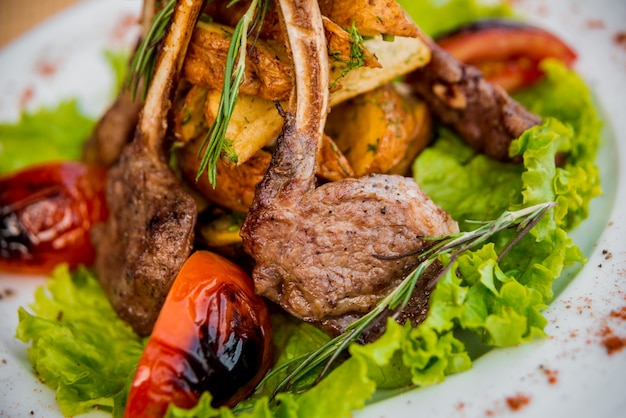 Viande sur l'os avec des légumes sur une plaque blanche.