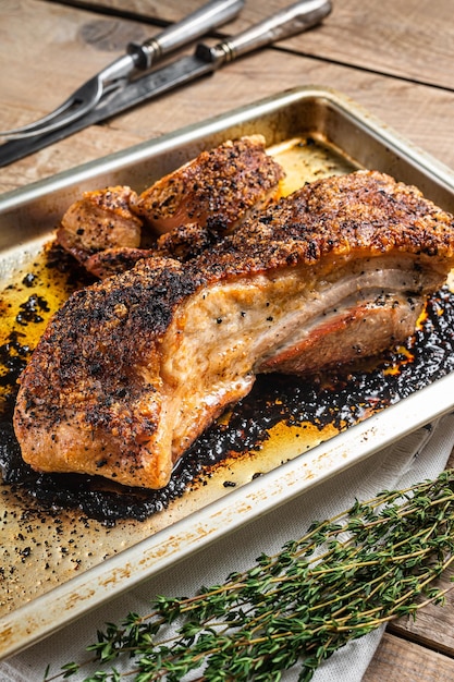 Viande de poitrine de porc rôtie au four dans un plateau de cuisine Fond en bois Vue de dessus