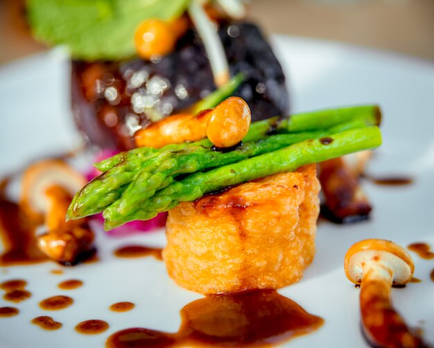 Viande avec pommes de terre et asperges sur une plaque blanche.