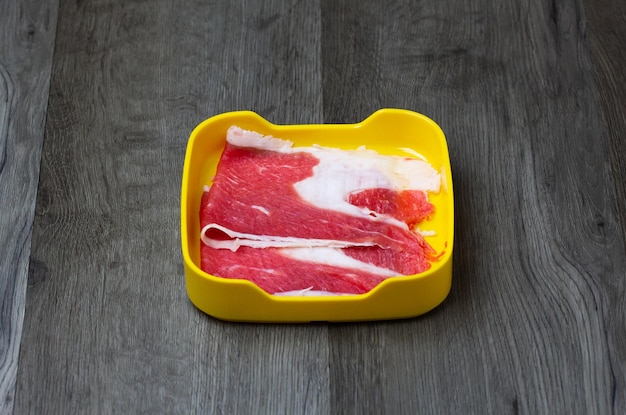 Viande de porc crue fraîche ventre de boeuf tranché sur une assiette carrée sur fond de bois en bois ingrédients shabu hot pot