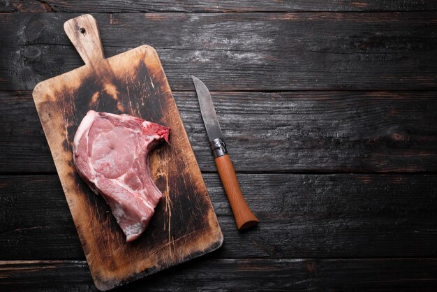 Viande de porc crue, un morceau frais se trouve sur une planche à découper, une table de cuisine en bois.