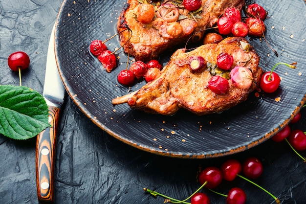 Viande de porc sur l'os rôtie dans une marinade de baies. Steaks de porc grillés dans une sauce au vin de cerise