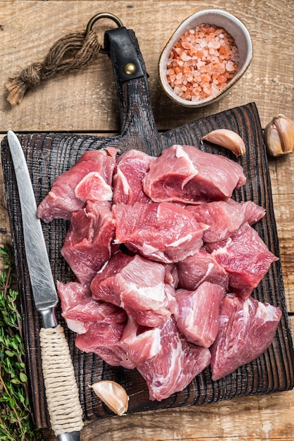 La viande de porcs en dés crus frais avec des épices sur une planche de boucher en bois