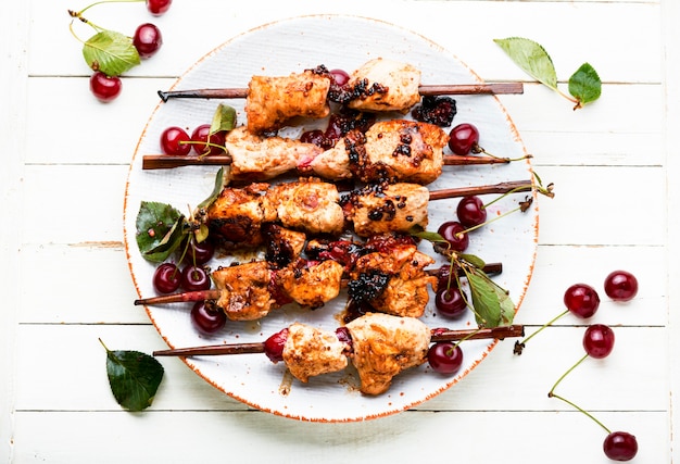 Viande de poulet sur des brochettes en bois dans une marinade aux cerises