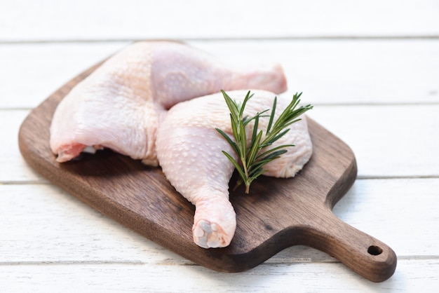 Viande de poulet crue au romarin - filet de cuisse de poulet cru frais sur fond de planche à découper en bois, vue de dessus