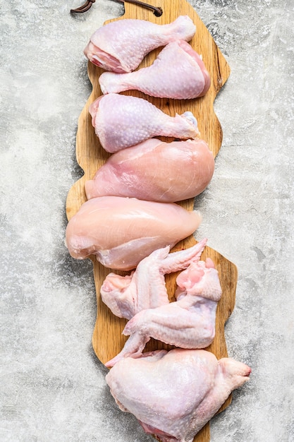 Viande de poulet crue non cuite sur une planche à découper. Fond gris. Vue de dessus.