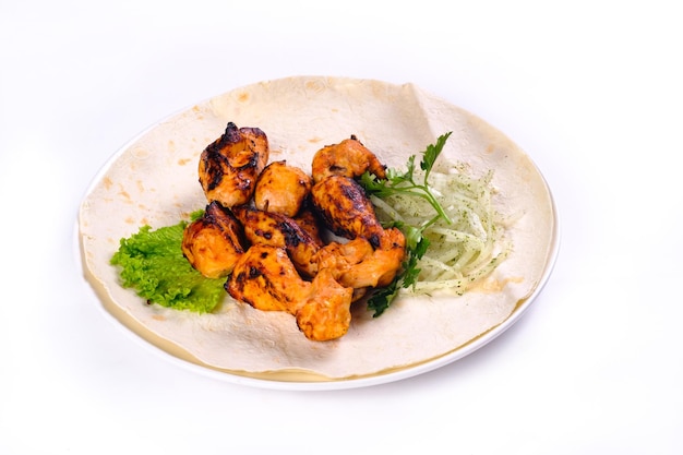 Viande de poulet sur du pain pita avec des légumes sur une plaque blanche sur un fond blanc isolé.