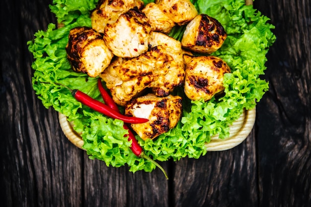 Viande de poulet sur le gril avec piment et laitue sur fond de bois