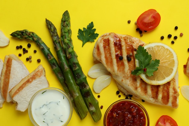 Viande de poulet grillé, asperges et ingrédients sur fond jaune