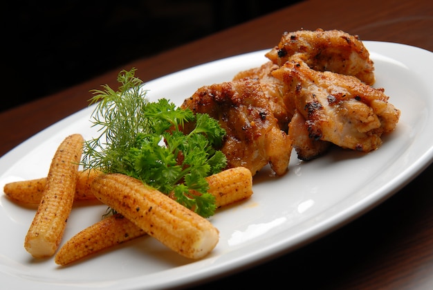 Viande de poulet grillée avec sauce et maïs sur une plaque