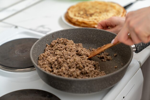 La viande de remplissage pour les crêpes est frite dans une poêle