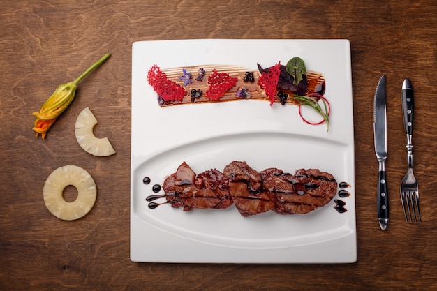 Viande rôtie à l&#39;ananas dans une sauce balsamique sur une planche de bois brune