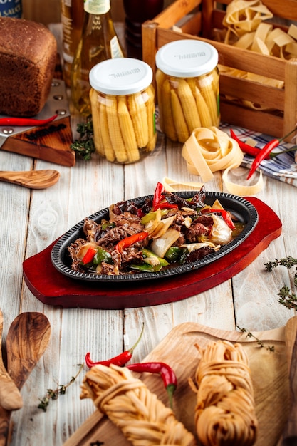 Viande rôtie aux légumes dans une poêle en fonte sur la table en bois