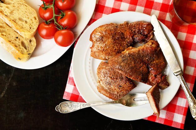 Viande rôtie et légumes sur plaque sur fond de table en bois