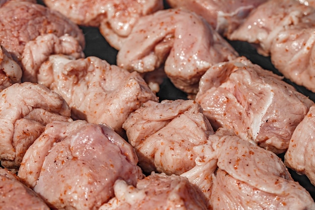 Photo la viande rouge crue avec des épices enfilées sur des brochettes en morceaux est frite sur des charbons en gros plan.
