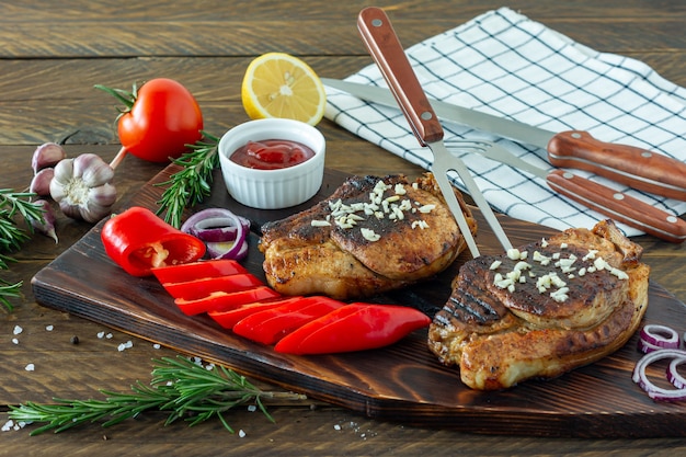 Viande rouge rôtie juteuse fraîche sur planche de bois, avec épices et légumes. Nourriture de restaurant, plat délicieux.