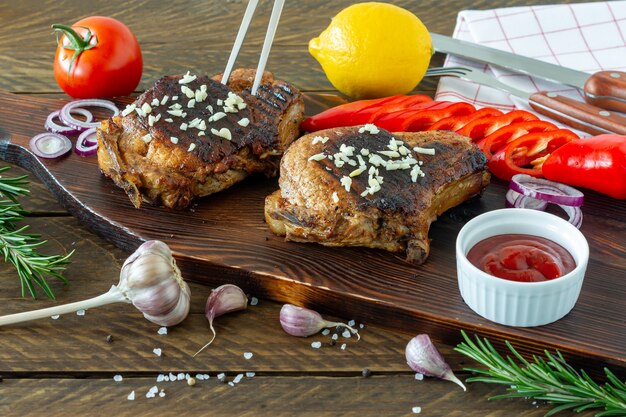 Viande rouge rôtie juteuse fraîche sur planche de bois, avec épices et légumes. Nourriture de restaurant, plat délicieux.