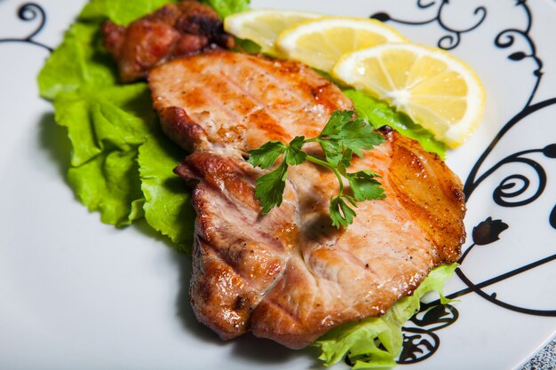 Viande avec salade et citron sur une assiette blanche