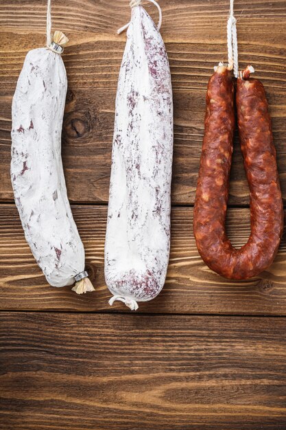 Viande de saucisses fumées espagnoles traditionnelles suspendues sur table en bois.