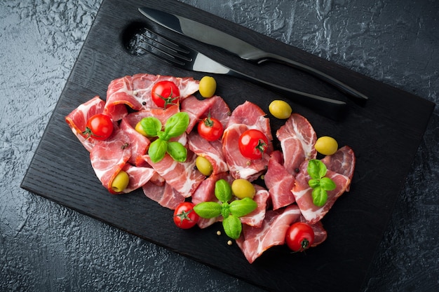 Viande séchée, jambon aux tomates cerises, basilic et olives sur fond noir