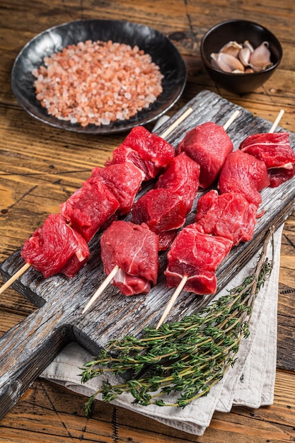 Viande de shish kebab de boeuf cru avec des épices et des herbes sur des brochettes Fond en bois Vue de dessus