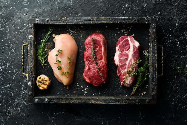 Viande steak de boeuf poitrine de poulet et porc Prêt à cuire Vue de dessus Sur un fond de pierre noire