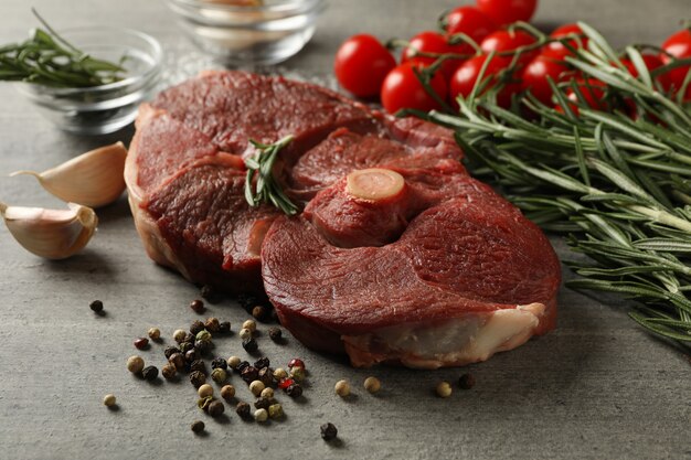 Viande de steak crue fraîche, herbes et épices sur table grise