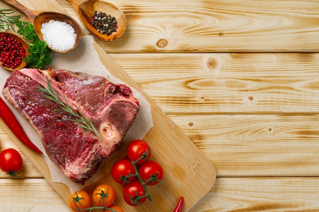 Viande De T-bone Crue Avec Des Légumes Frais Et Du Romarin Sur La Table