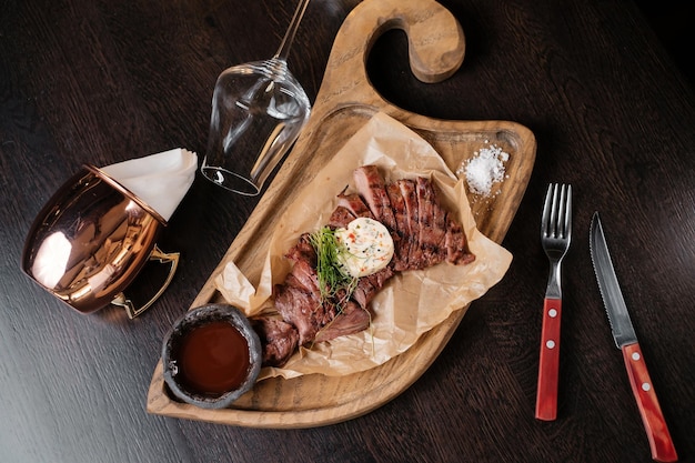 Viande tranchée sur une planche de bois avec des sauces