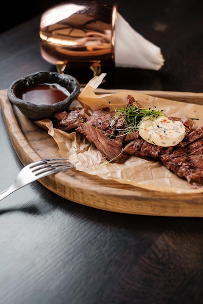 Viande tranchée sur une planche de bois avec des sauces