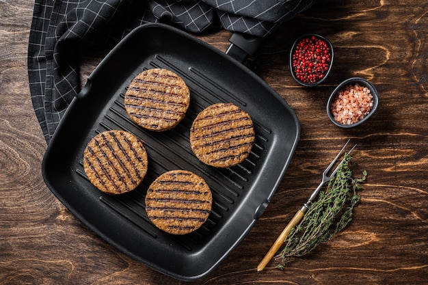 Photo viande végétarienne grillée à base de galettes de burger escalopes végétaliennes sur une poêle à griller fond en bois vue de dessus