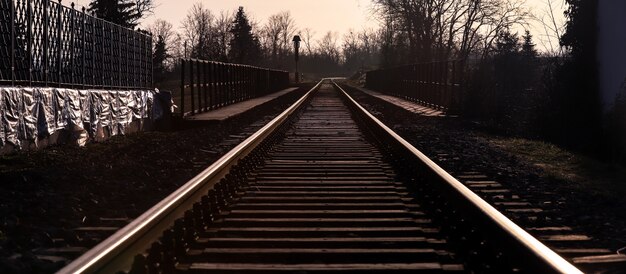 Vías antiguas de tren al anochecer pasando por un puente de Autriche.