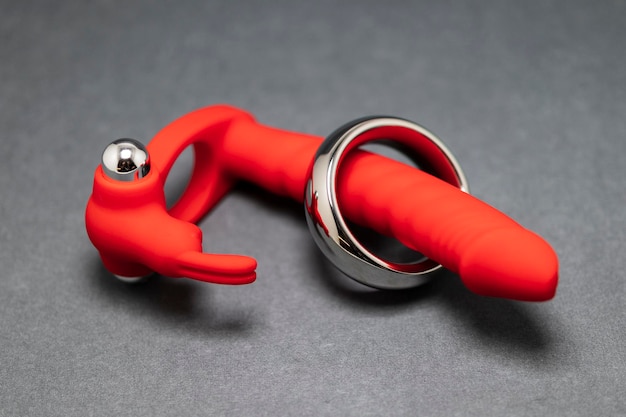 Vibromasseur anal rouge jouet sexuel avec un lapin et un anneau pénien en métal sur fond gris en gros plan