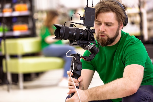 Vidéaste tournage d'un film ou d'une émission de télévision dans un studio avec une caméra professionnelle, dans les coulisses