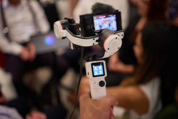 Photo videographe professionnel en capuche noire tenant une caméra professionnelle sur un stabilisateur de gimbal à 3 axes cinéaste réalisant une excellente vidéo avec une caméra de cinéma professionnelle cinématographe