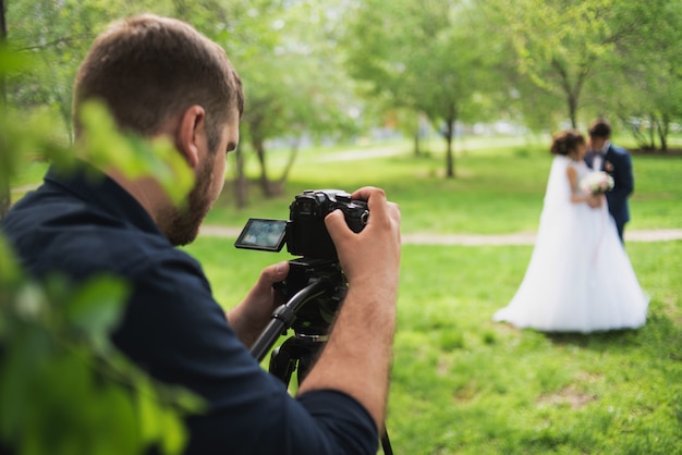 Photo le vidéographe tourne les mariés dans le jardin en été.