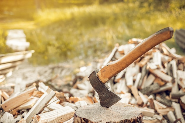 La vie du village Une hache dans la souche avec beaucoup de bois de chauffage coupé à l'arrière-plan