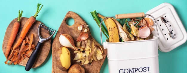 Vie durable et zéro déchet Déchets végétaux dans le pot de compost de recyclage Vue de dessus Espace de copie Légumes pelés sur une planche à découper bac à compost blanc sur fond bleu Recycler les déchets de cuisine