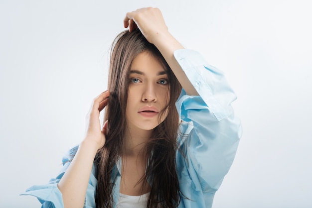 Vie épuisée. Réfléchissant belle femme regardant droit et touchant les cheveux tout en étant perdu dans les rêves