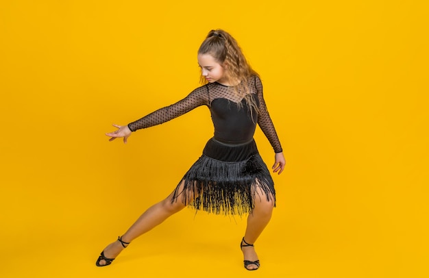 La vie en mouvement. enfant en posture de danse. slowfox et quickstep professionnels. valse et tango. vêtements de mode de danse. école de danse. danseuse de salon adolescente. enfant dansant en robe noire.